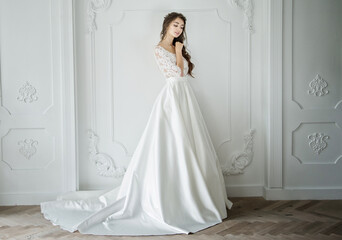 Portrait of a young bride in a fashionable wedding dress with beautiful makeup and hairstyle