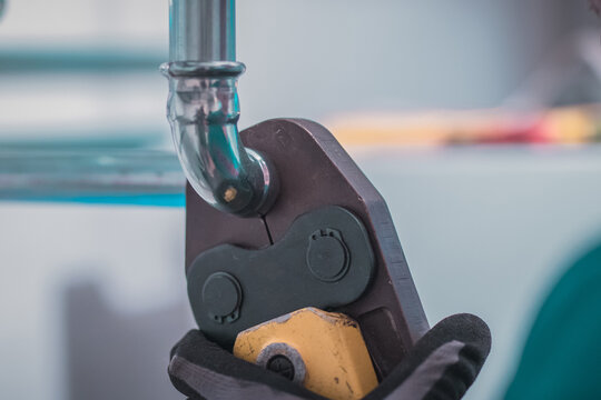 Plumber using pipe fastener or battery press tool to crimp heating or warm water pipes together. House renovation.