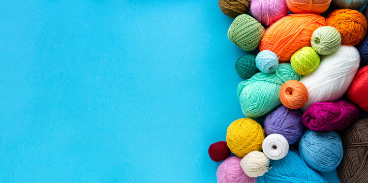 Knitting flat lay. Various colored balls of yarn on a blue background. Space for text