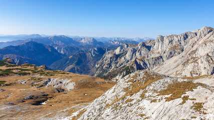 Panoramic view on mountains in Hochschwab region, Austrian Alps. The flora overgrowing slopes is golden. Autumn vibes in the mountains. Endless mountain chains shrouded in fog. Freedom and wilderness