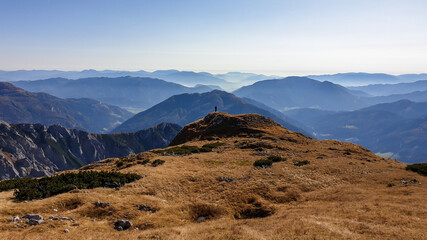 Panoramic view on mountains in Hochschwab region, Austrian Alps. The flora overgrowing slopes is golden. Autumn vibes in the mountains. Endless mountain chains shrouded in fog. Freedom and wilderness