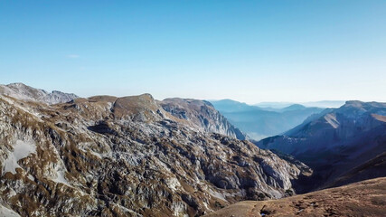 Obraz premium A panoramic view on the plain on top of a mountain in Hochschwab region in Austrian Alps. The flora overgrowing the slopes is turning golden. Autumn vibes. Sharp and steep mountain chain. Wilderness