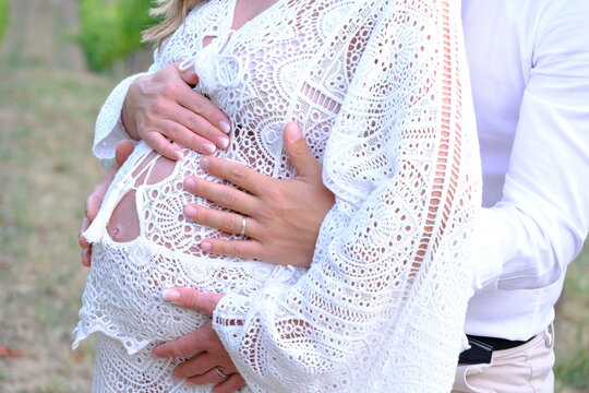 Coppia con donna incinta. Gravidanza e attesa di una coppia con vestito bianco. Abbraccio