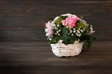Artificial flowers in a basket. Wicker basket with ornamental flowers. Bouquet in the basket. Decorative flowers as a gift.