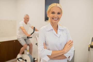Obraz premium Blonde doctor smiling and standing with her arms crossed