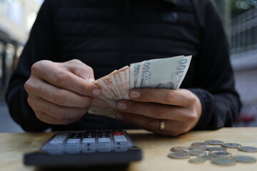 man doing financial transactions with calculator holding money in hand.