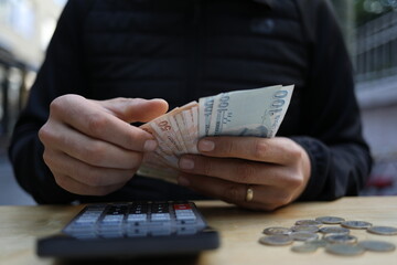 man doing financial transactions with calculator holding money in hand.