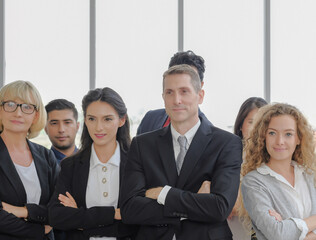 Candid multi ethnic business people concept. Senior male executive manager leading stands confident arms crossed with staff together at the office conference room.