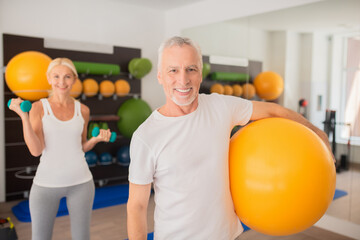 Fototapeta na wymiar Man with a ball and a woman with dumbbells exercising together