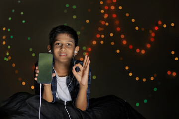 Cute indian little child showing smart phone screen and giving expression