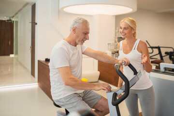 Man on a treadmill talking to his female instructor and looking involved