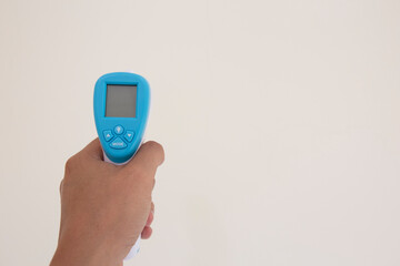 close up of a hand holding a digital infrared thermometer (thermometer gun) isolated on white