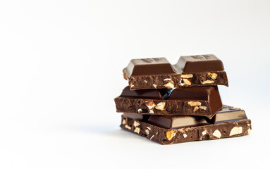 hazelnut milk or dark chocolate pieces tower isolated on white background, a stack of chocolate squares with nuts