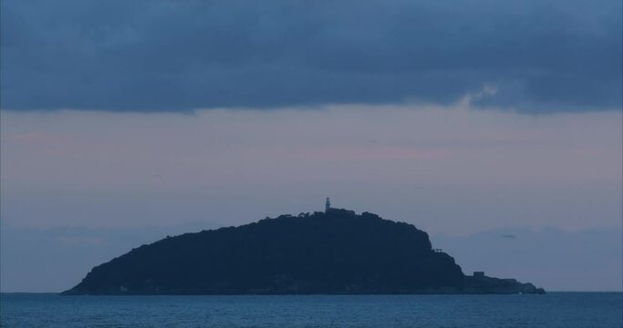 Timelapse Sky and sea with lighthouse of the Tino island. The clouds flow quickly in the sky and the lighthouse on the island emits flashes of light. Video footage royalty free. La Spezia, Italy. Abou
