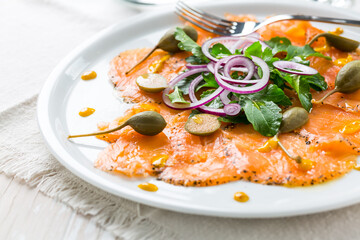 Salmon carpaccio and arugula salad with onions and capers
