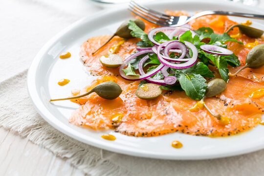 Salmon carpaccio and arugula salad with onions and capers