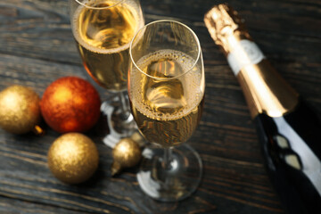 Champagne bottle and glasses, and baubles on wooden table