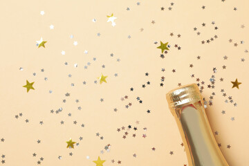 Champagne bottle and glitter on beige background