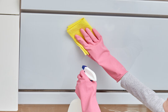 Women's hands in pink rubber gloves doing cleaning in the kitchen. Modern bright kitchen. Performing a home routine. Cleanliness in the house.