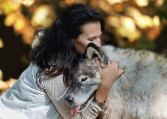 Young woman hugs her dog in the autumn forest