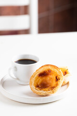 Black coffee bica and famouse pastel de nata (egg tart pastry) and orange juice on white table at Lisboa coffee shop. Portuguese breakfast concept.