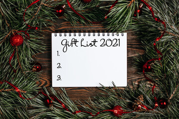 Fototapeta na wymiar Merry christmas and merry new year concept with gift boxes, toys and notebook with text Gift List 2021