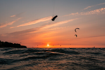 Kitesurfer doing a massive jump in front of a beautiful sunset at the baltic sea