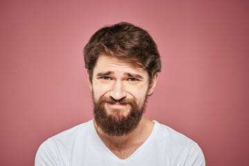 Obraz premium Emotional bearded man in white T-shirt discontent pink background