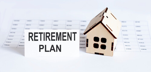 Closeup of house wooden model with blank for text Retirement Plan on chart background.