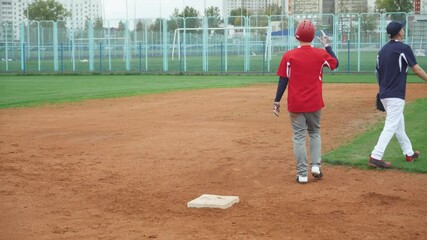 College, baseball training day, the catcher and runner run on base, the catcher is ahead of the runner, guys are training to play baseball. - Powered by Adobe