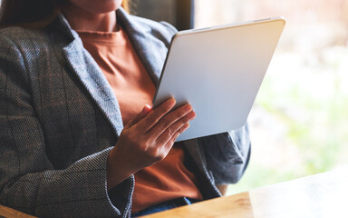 Closeup image of a woman holding and using digital tablet