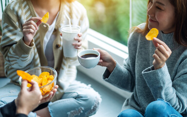 Closeup image of friends drinking and eating potato chips together