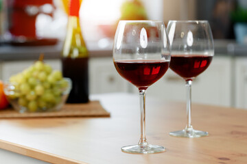 Two wine glasses with red wine on wooden kitchen counter