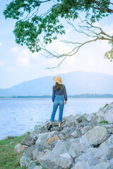 Obraz premium portrait woman stand on the rock in sea landscape with mountain relax and calm in sunny day concept vacation, relaxing, positive thinking