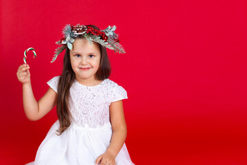 mock-up portrait of a happy girl in a festive dress, holding a caramel cane in her hand, on a red background.