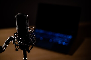 Close-up of a professional microphone on the background of a laptop in the dark