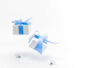 Christmas gift. White gift box with blue ribbon, New Year balls in xmas composition on white background for greeting card. Winter festive composition with copy space.