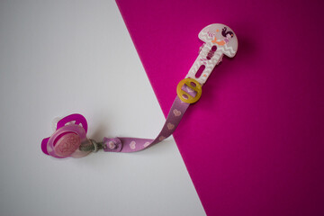 Baby pacifier on white and pink diagonally divided background