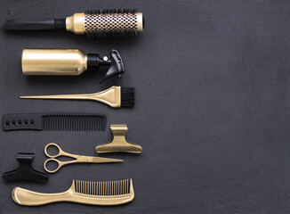 Hairdressing tools in black and gold on a gray concrete background. Hair salon accessories, combs,...