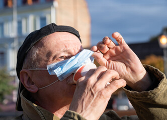 Senior man with face medical mask drinking a cup of coffee