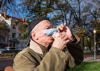 Senior man with face medical mask drinking a cup of coffee