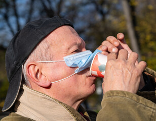 Senior man with face medical mask drinking a cup of coffee