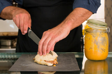 male hands of a chef make meat sandwiches with beef and sandwich and empanadas, traditional tasty latin food, with meet or vegetarian in a fancy bakery in Lisbon . Process of making sandwiches