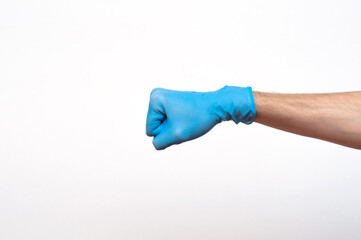 Doctor's hand in a blue surgical glove strikes, photo in the studio on a white background isolated. Fighting the disease with the help of doctors. Influence of medicine on the disease.