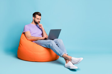 Full length body size photo of confident businessman working on computer in beanbag isolated on vibrant blue color background copyspace