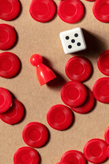 Playing board games detail, overhead flat lay shot of a die with a red pawn and pieces on a brown...