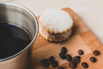 Italian american black coffee in a vintage cup with coffee beans around and a handmade cookie with sugar and a moka pot behind. Everything in vintage wood background 