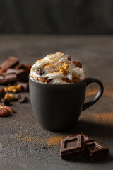 Hot chocolate cocoa cup with whipped cream decorated with cinnamon, chocolate slice and nuts  on concrete background. Traditional beverage for cold days concept.