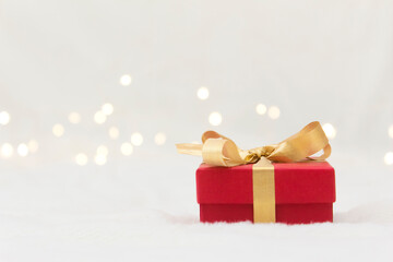 Red gift box with a gold bow on a light background.