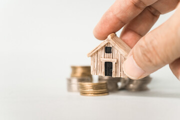 miniature house in old people hand with blurred stack of coins , business and finance background